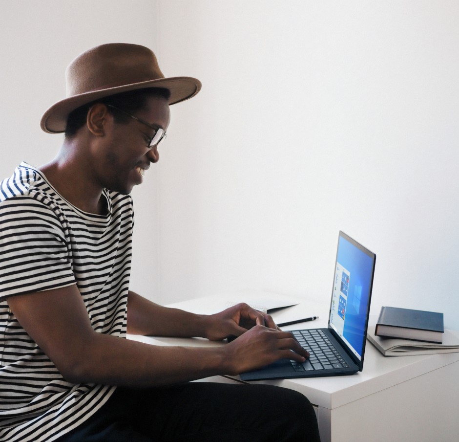 A smiling and stylish Black man uses his laptop to learn new business skills.