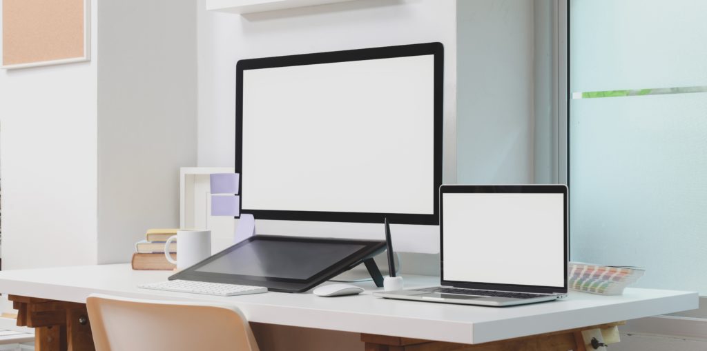 a desktop computer, laptop computer, and digital tablet on a desk.