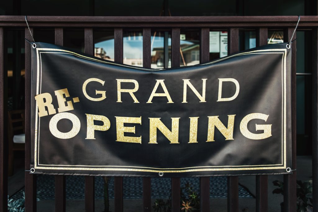 black banner with "grand re-opening" printed on it in gold uppercase letters.