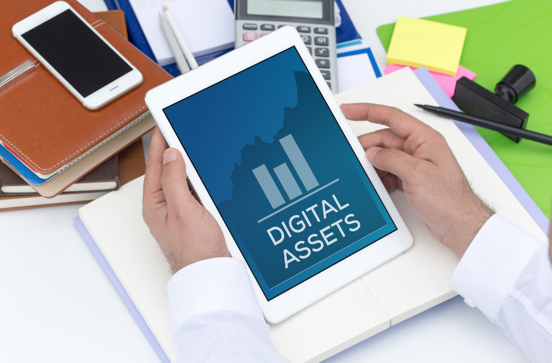blog titlecard for Digital Branding Assets For Every Business: person holding iPad on a busy desk with iPhone and business assets